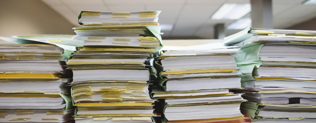 Picture of piled up documents with post-it notes sticking out.