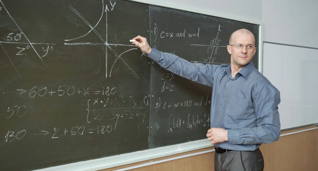 Image of person explaining mathematical things on a blackboard.